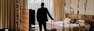 Mann mit Koffer im Deluxe Zimmer