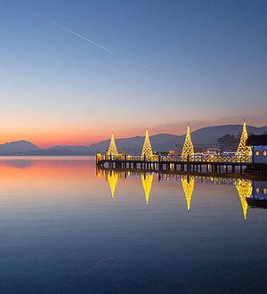 Der Wörthersee mit beleuchteten Häusern in der Abenddämmerung