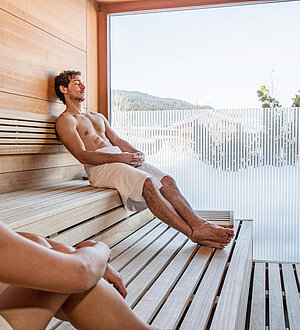 Mann und Frau in der Sauna mit Ausblick