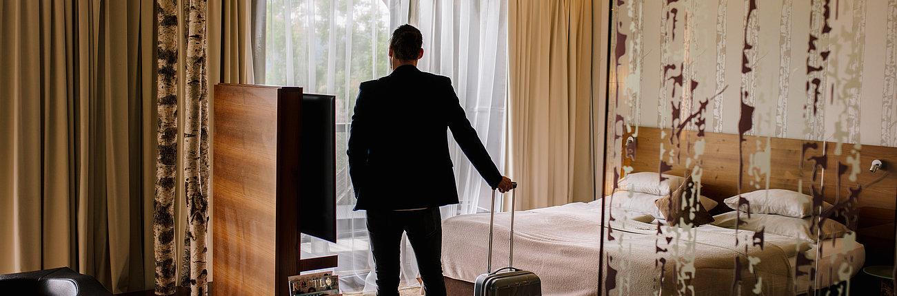 Mann mit Koffer im Deluxe Zimmer