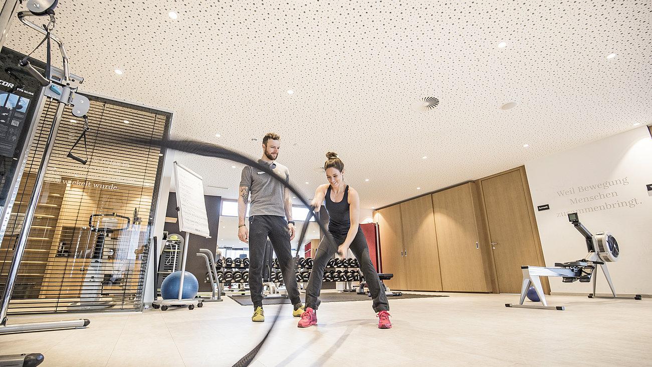 Trainer sieht einem Gast bei einer Sportübung zu